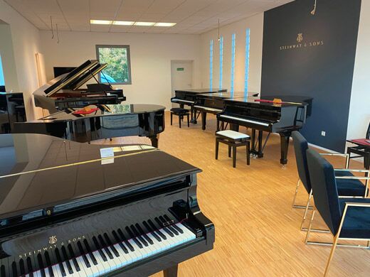 Ausstellung von Piano Hoffmann mit schwarzen Flügeln vor der Steinway-&-Sons-Wand