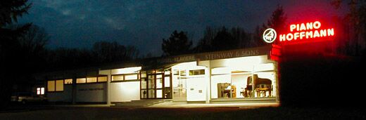 Das Klavierhaus Piano Hoffmann in Neuhofen am Abend mit beleuchtetem Schriftzug
